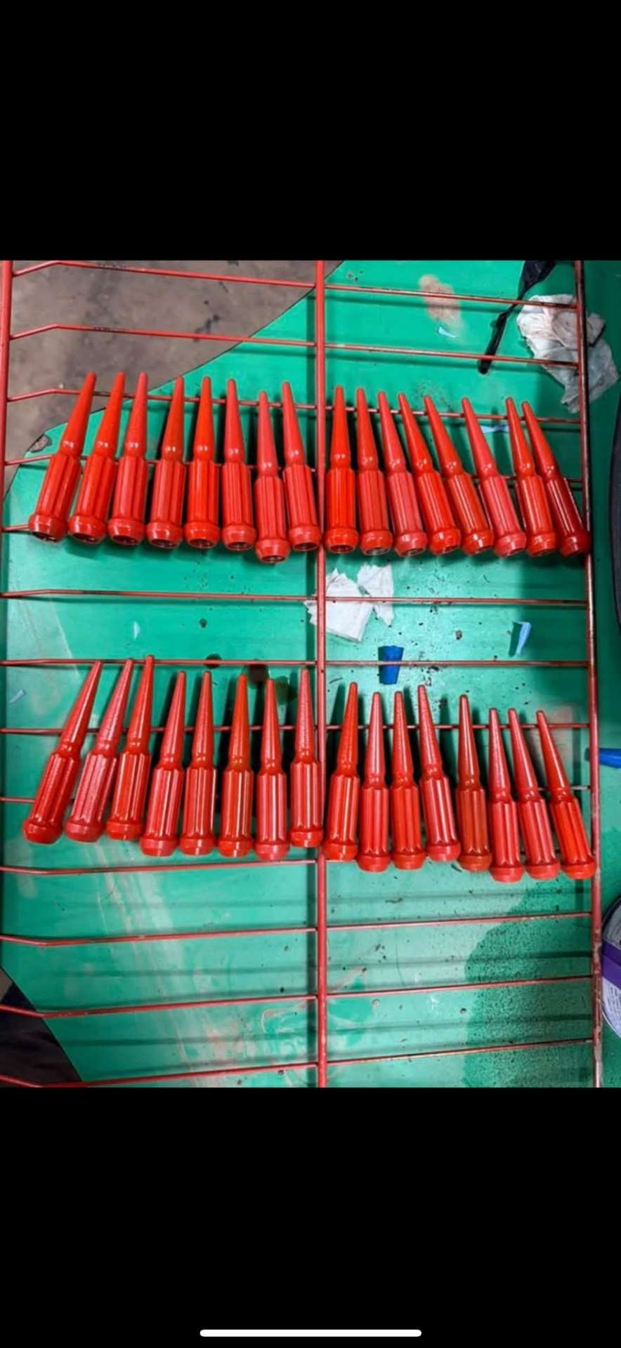 Red spike lug nuts on curing rack